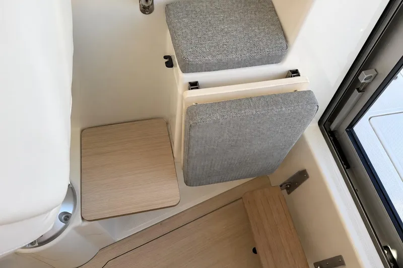 Slide: The Image of 2025 Bayliner Trophy T23 Pilothouse interior seating with foldable cushions and wooden accents. - 16