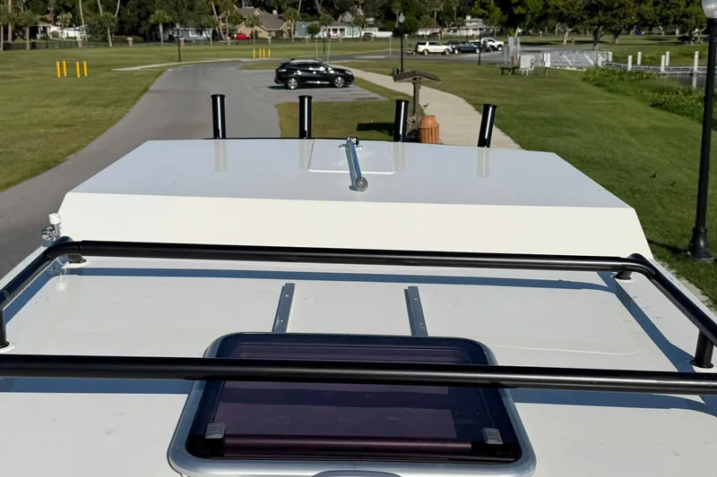 Slide: The Image of 2025 Bayliner Trophy T23 Pilothouse roof view with scenic park background. - 8