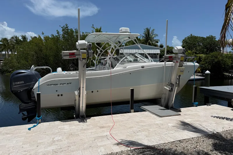 The Image of 2018 World Cat 255 DC boat on lift, surrounded by tropical scenery. - 1
