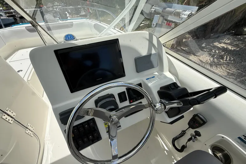 Slide: The Image of 2018 World Cat 255 DC boat dashboard with steering wheel and navigation controls. - 12