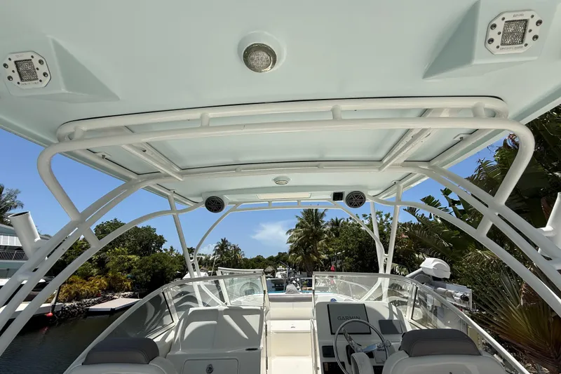 Slide: The Image of 2018 World Cat 255 DC boat interior with canopy, steering wheel, and lush surroundings. - 16