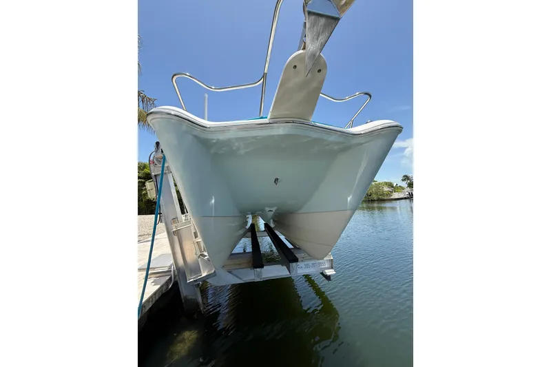 Slide: The Image of 2018 World Cat 255 DC boat on lift, docked by calm water under clear blue sky. - 4