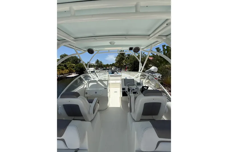 Slide: The Image of 2018 World Cat 255 DC boat interior with seating and steering wheel, docked near lush greenery. - 6