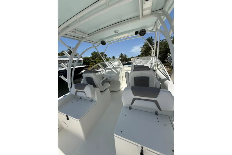 Slide: The Image of 2018 World Cat 255 DC boat interior with seating and canopy, docked near lush greenery. - 7