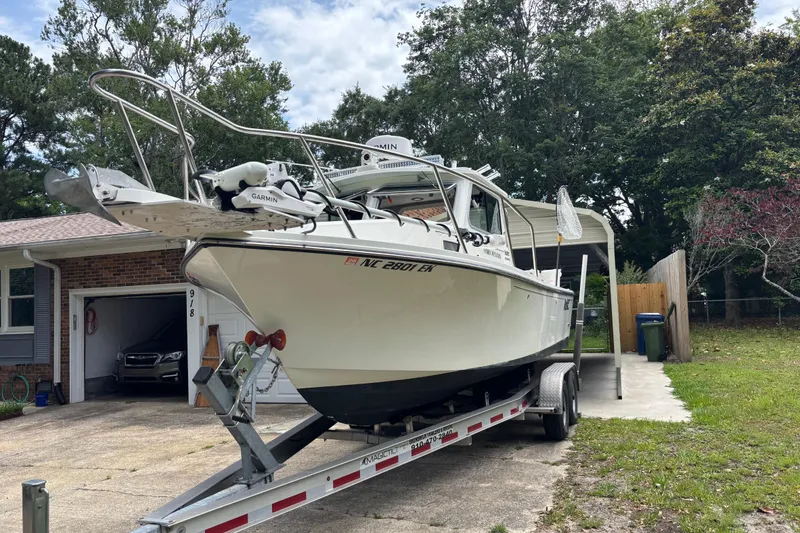 Slide: The Image of 2019 Parker 2320 SL Sport Cabin boat on trailer in driveway, surrounded by trees. - 2