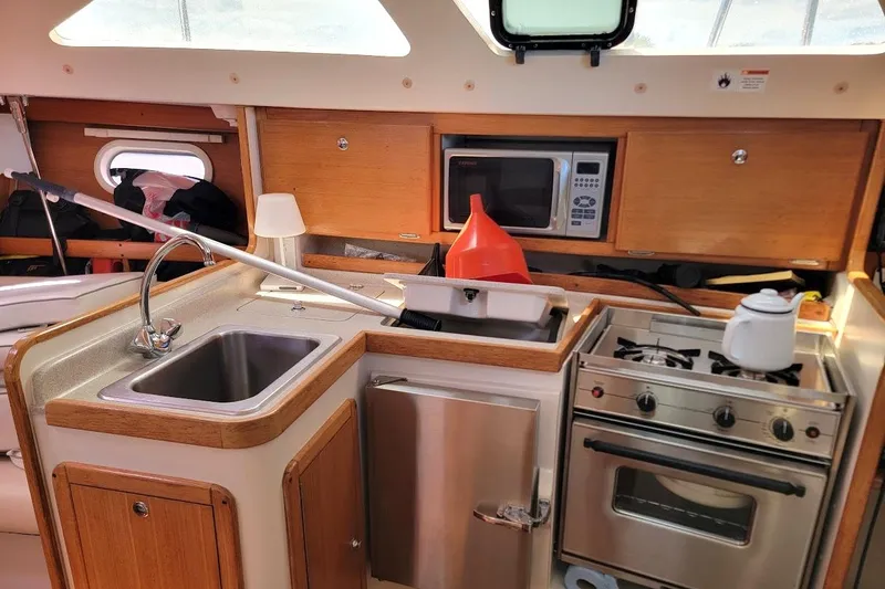 Slide: The Image of Compact kitchen in a 2006 Catalina 310 sailboat with sink, stove, and microwave. - 15