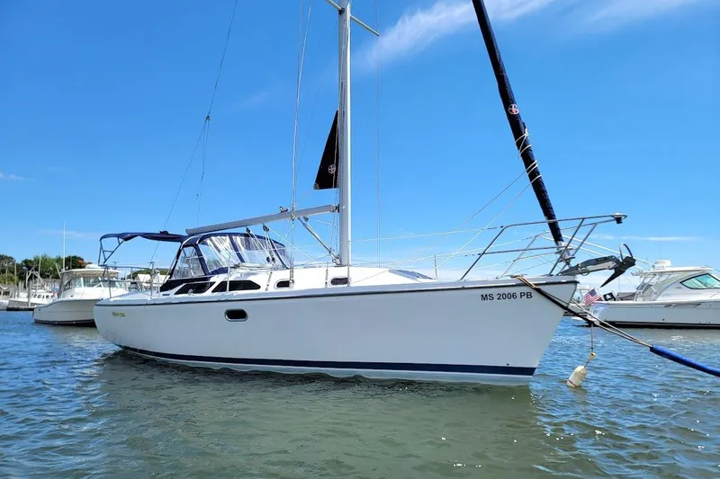 Slide: The Image of 2006 Catalina 310 sailboat anchored in a marina under clear blue skies. - 26