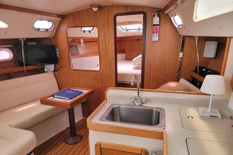 Slide: The Image of Interior of a 2006 Catalina 310 sailboat with cozy seating and kitchenette. - 21