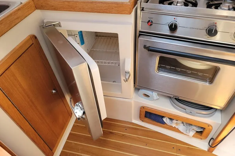 Slide: The Image of Catalina 310 yacht kitchen with open fridge and stainless steel stove, 2006 model. - 9