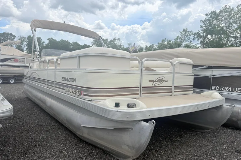 The Image of 2001 Bennington 2200 FS pontoon boat parked on gravel lot under cloudy sky. - 0