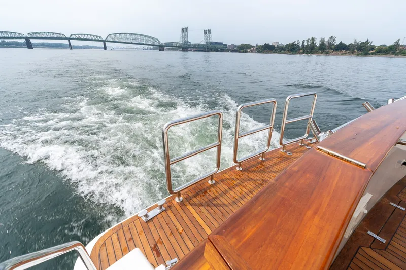 Slide: The Image of 2009 Outer Reef Yachts Motor Yacht cruising near a bridge, showcasing wooden deck and wake. - 60