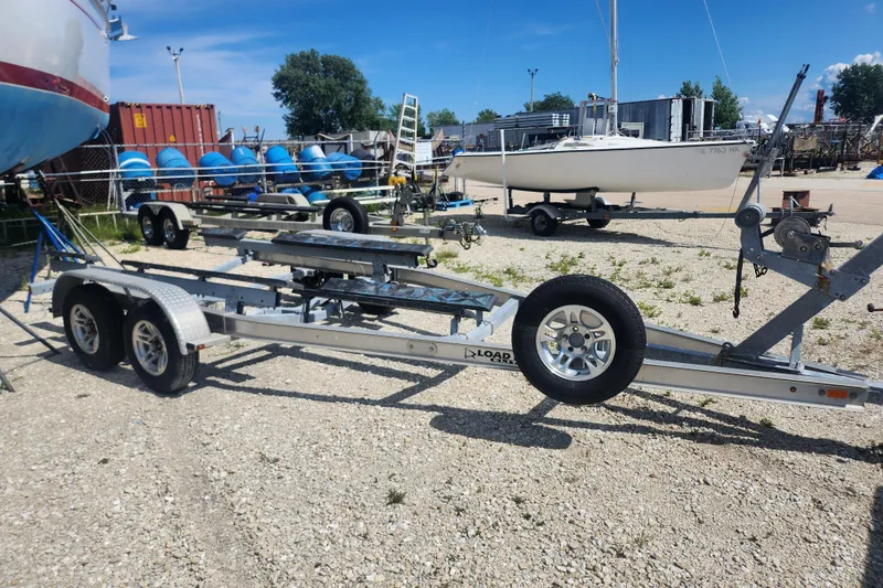 Slide: The Image of Boat trailer parked in a gravel lot, surrounded by boats and equipment. - 12