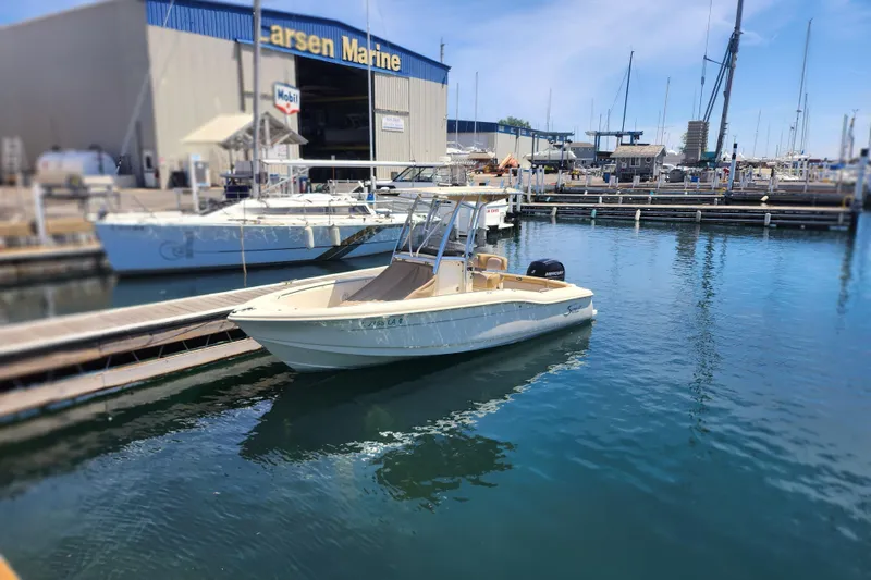 Slide: The Image of 2014 Scout 210 XSF boat docked at a marina with clear blue water. - 2