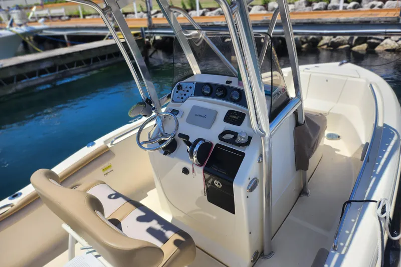 Slide: The Image of 2014 Scout 210 XSF boat interior with steering console and seating at the dock. - 5
