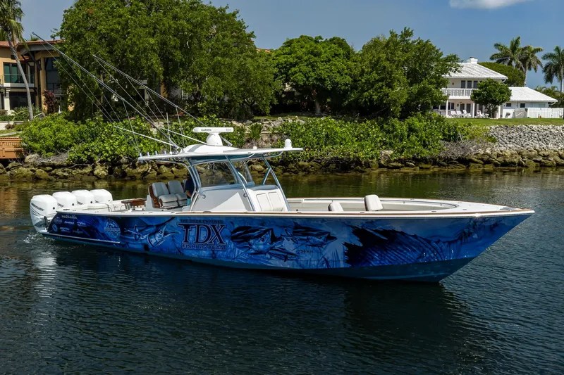 Slide: The Image of 2020 Valhalla Boatworks V-41 with custom blue graphics, docked near lush greenery. - 4