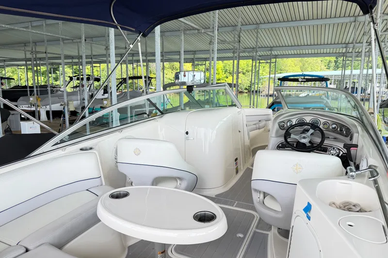 Slide: The Image of Interior of a 2010 Bryant 255 boat docked, featuring seating and steering wheel. - 12
