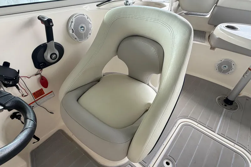 Slide: The Image of Captain's chair in a 2010 Bryant 255 boat cockpit, featuring steering wheel and controls. - 22