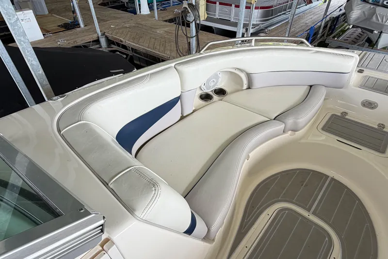 Slide: The Image of 2010 Bryant 255 boat interior with white and blue seating, docked at marina. - 29