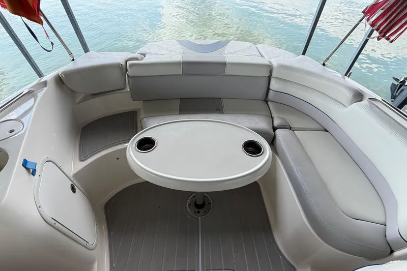 Slide: The Image of 2010 Bryant 255 boat interior with curved seating and table on calm water. - 37