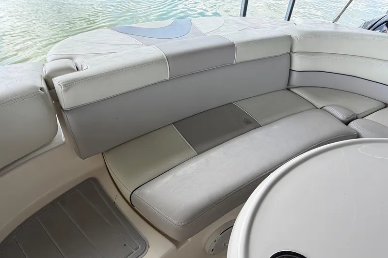 Slide: The Image of 2010 Bryant 255 boat interior with cushioned seating and table, near water. - 47