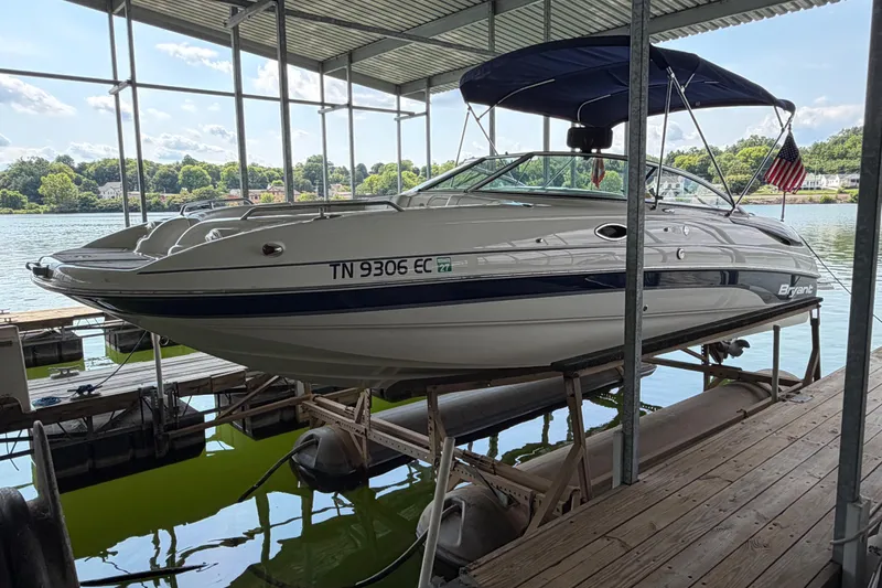 Slide: The Image of 2010 Bryant 255 boat docked on a lift, with scenic lake background. - 5