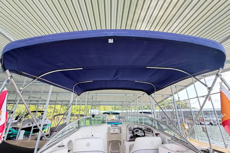 Slide: The Image of 2010 Bryant 255 boat with blue canopy docked under a metal roof. - 51