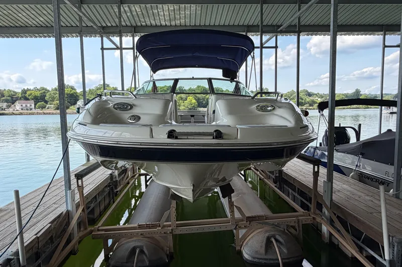 Slide: The Image of 2010 Bryant 255 boat docked under a covered marina with scenic lake view. - 52