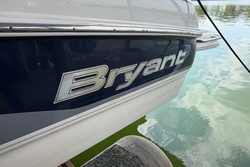 Slide: The Image of 2010 Bryant 255 boat side view on water, showcasing brand logo. - 55