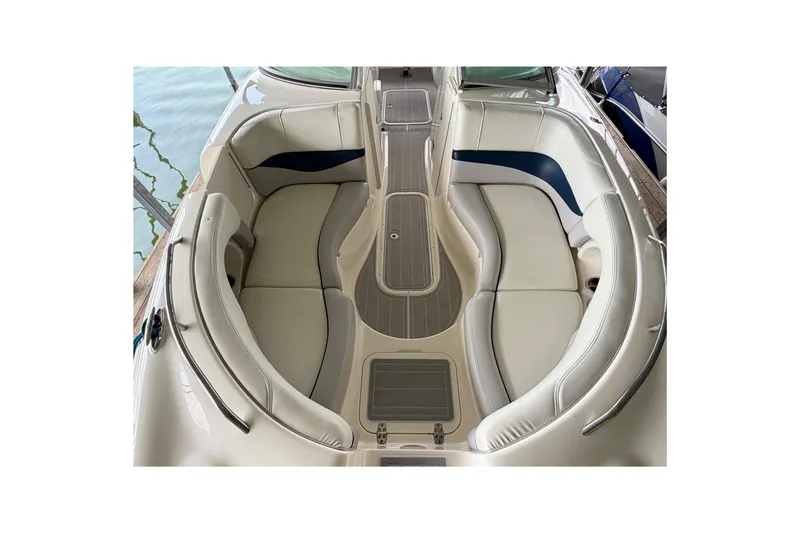 Slide: The Image of 2010 Bryant 255 boat interior with white and blue seating, docked by the water. - 6