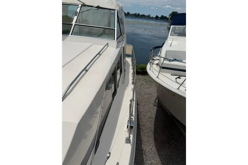 Slide: The Image of 1980 Chris-Craft 381 Catalina yacht docked beside another boat, near a serene waterway. - 10