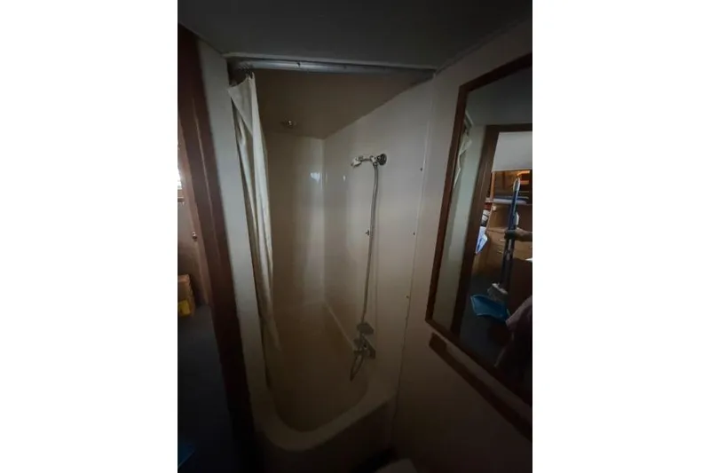 Slide: The Image of Shower area inside 1980 Chris-Craft 381 Catalina yacht, featuring a curtain and handheld showerhead. - 26