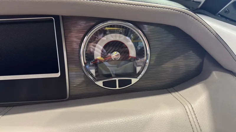 Slide: The Image of Close-up of a tachometer in a 2022 Four Winns HD5 boat, surrounded by gray leather. - 26