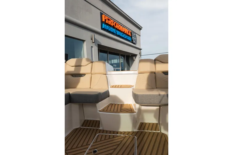 Slide: The Image of 2026 MasterCraft XStar 23 boat interior with tan seating and teak flooring at a marine dealership. - 16