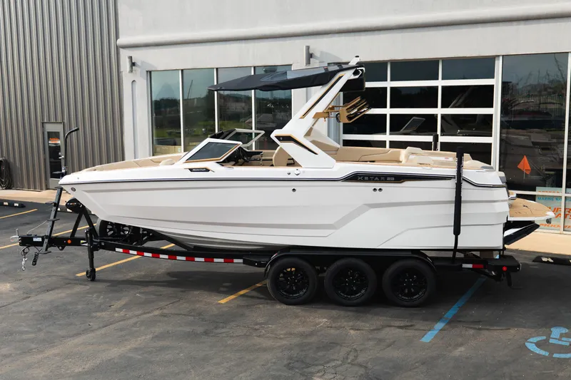 Slide: The Image of 2026 MasterCraft XStar 23 boat on trailer, parked outside a modern building. - 3