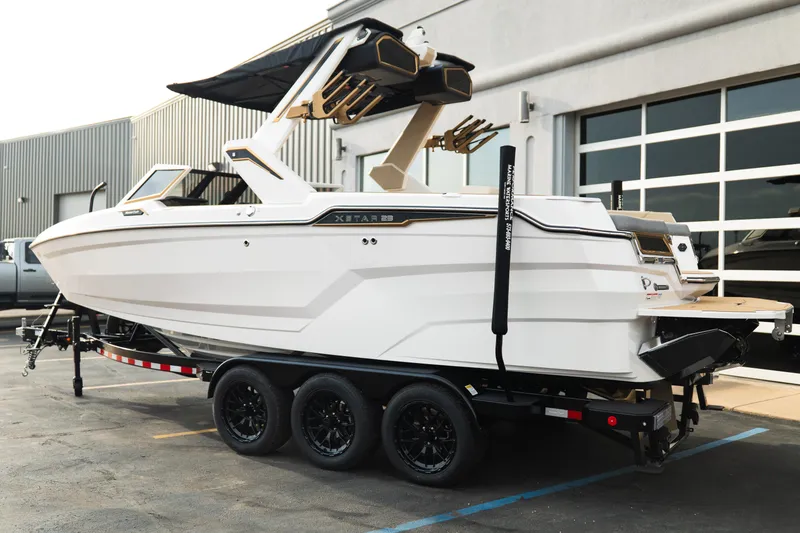 Slide: The Image of 2026 MasterCraft XStar 23 boat on trailer, parked outside a modern building. - 4
