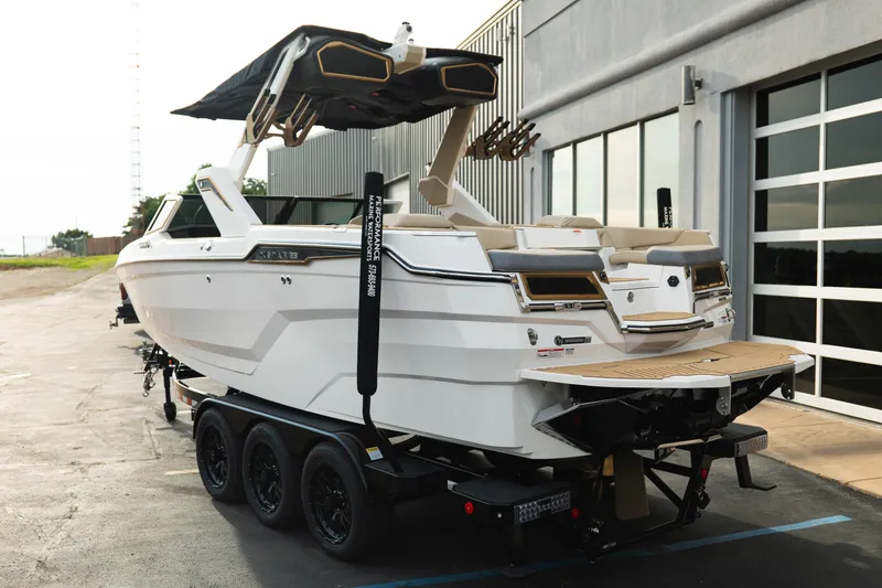 Slide: The Image of 2026 MasterCraft XStar 23 boat on trailer, parked outside a modern building. - 5