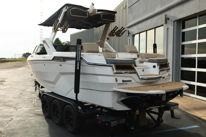 Slide: The Image of 2026 MasterCraft XStar 23 boat on trailer, parked outside a modern building. - 6