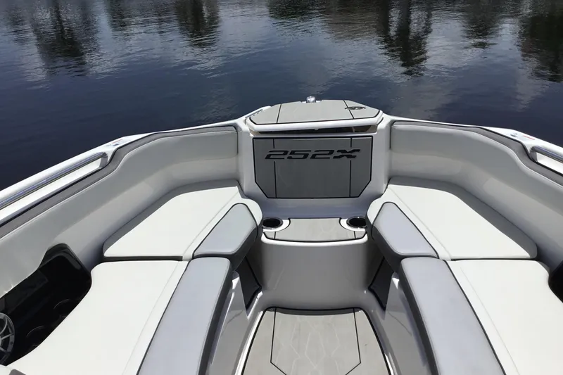 Slide: The Image of 2023 Yamaha Boats 252XE interior with cushioned seating and cup holders on calm water. - 14