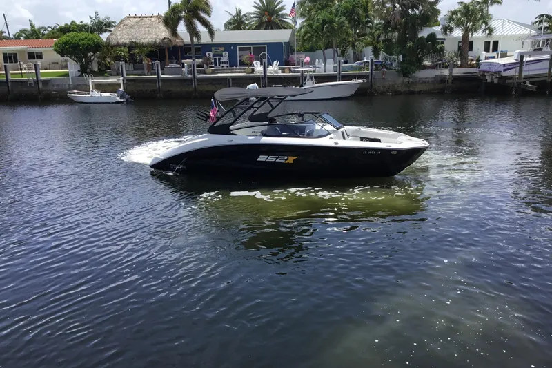 Slide: The Image of 2023 Yamaha Boats 252XE cruising on a sunny waterfront with palm trees. - 8