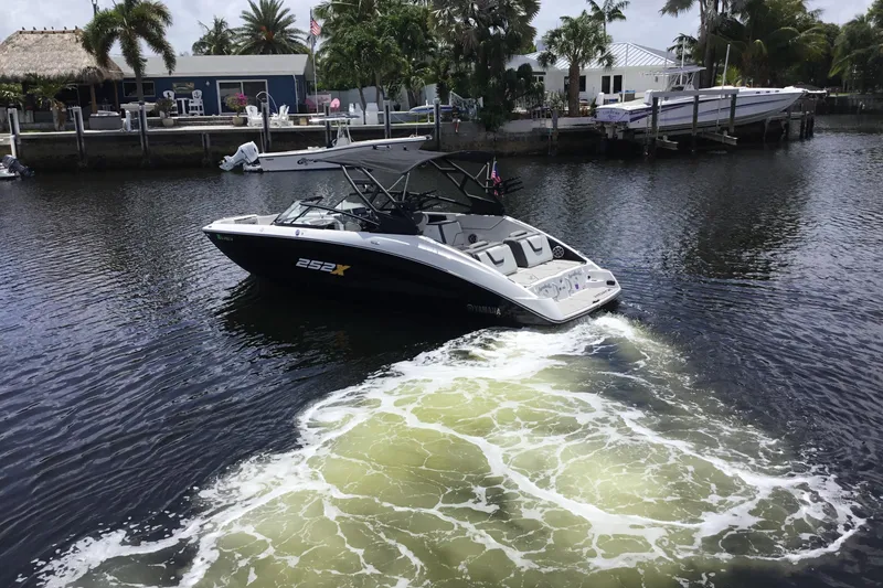 Slide: The Image of 2023 Yamaha Boats 252XE cruising on a scenic waterway with palm trees in the background. - 4