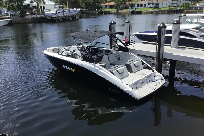 Slide: The Image of 2023 Yamaha Boats 252XE docked in a serene marina setting. - 40