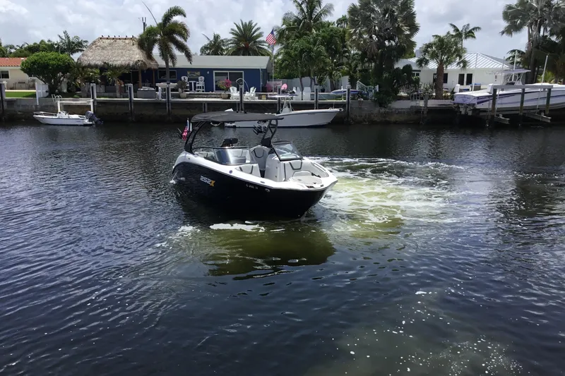 Slide: The Image of 2023 Yamaha Boats 252XE navigating a scenic canal with waterfront homes and palm trees. - 7