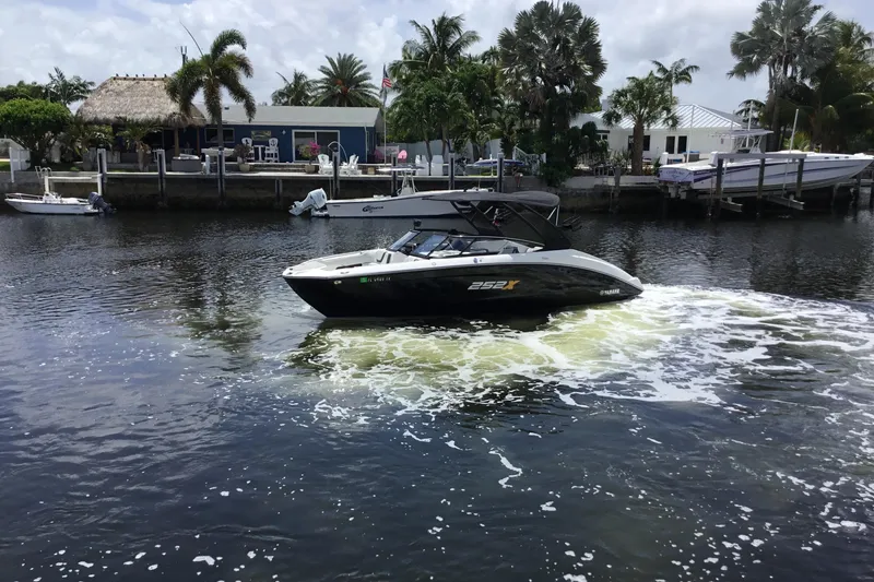 Slide: The Image of 2023 Yamaha Boats 252XE cruising on a scenic waterway with palm trees in the background. - 11