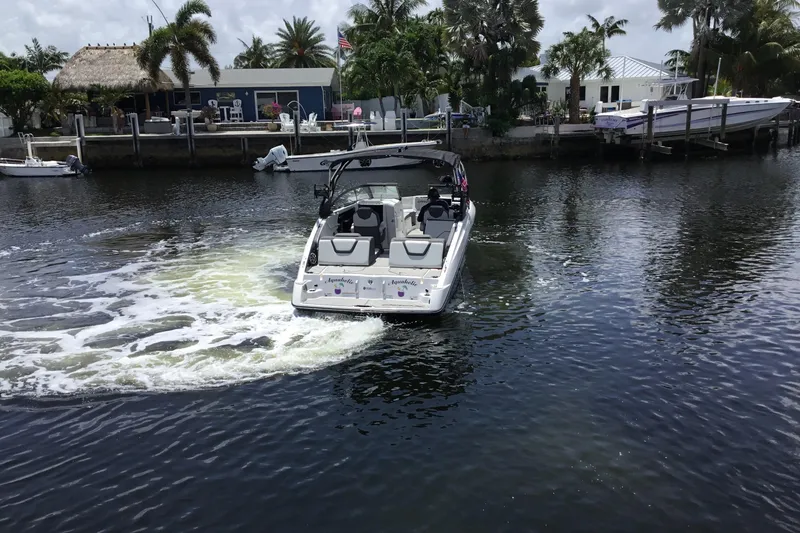 Slide: The Image of 2023 Yamaha Boats 252XE cruising on a scenic waterway near waterfront homes. - 10