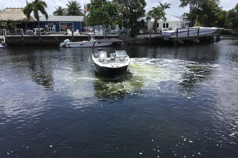 Slide: The Image of 2023 Yamaha Boats 252XE navigating a calm waterway near a dock with palm trees. - 12