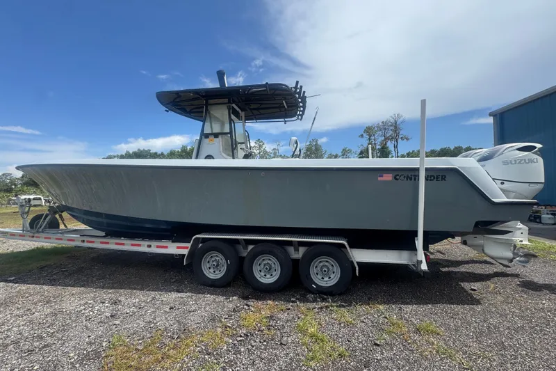 Slide: The Image of 2007 Contender 33 Tournament boat on trailer, featuring Suzuki engines, parked outdoors. - 2