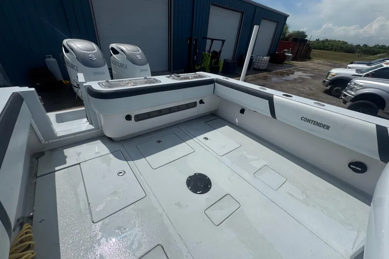 Slide: The Image of 2007 Contender 33 Tournament boat deck with Suzuki engines, parked near a blue building. - 20