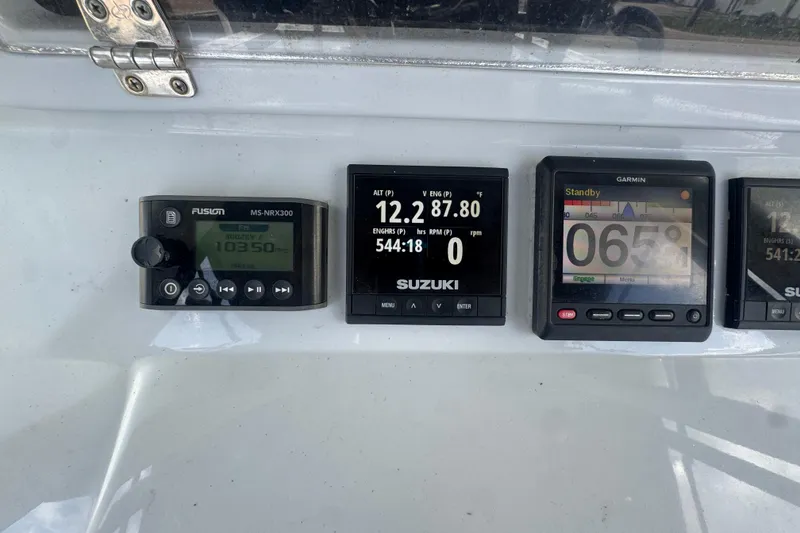 Slide: The Image of Boat dashboard with Fusion, Suzuki, and Garmin displays on a 2007 Contender 33 Tournament. - 33