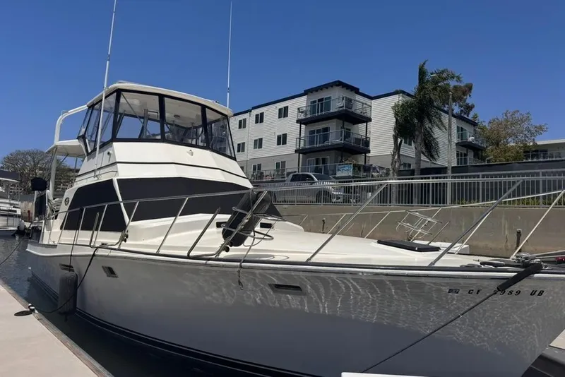 Slide: The Image of 1982 Sunliner Ocean Yachts docked near modern apartments, under a clear blue sky. - 1