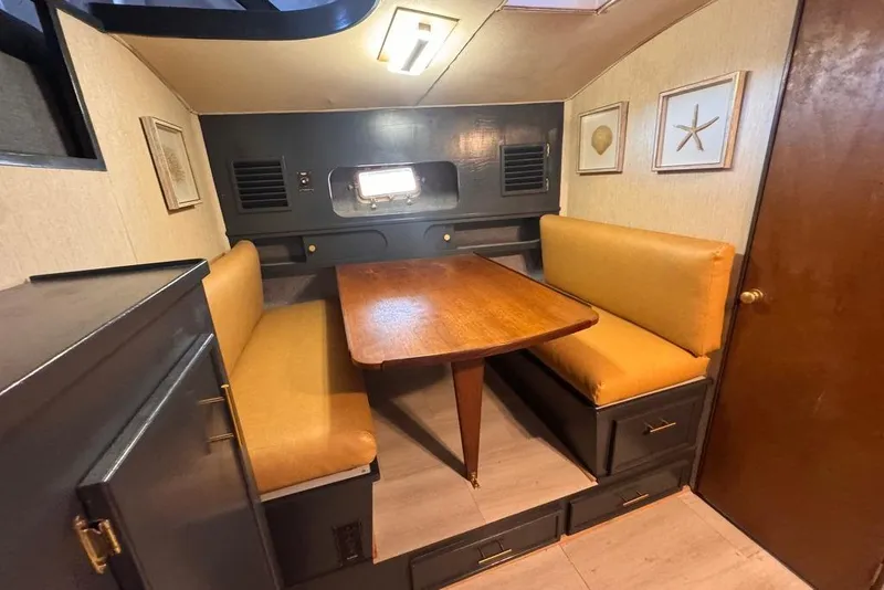 Slide: The Image of 1982 Sunliner Ocean Yachts interior with cozy dining area, wooden table, and cushioned seating. - 35